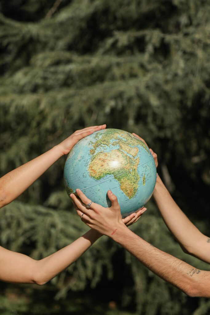 pexels-photo-6963622-6963622 Four hands holding a globe outdoors, symbolizing unity and environmental conservation.